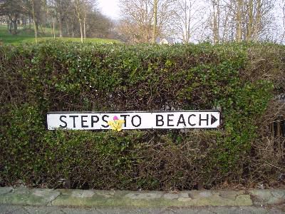 Infront of a sign "Steps To Beach"