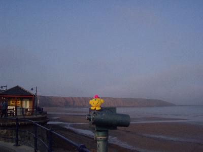 Sat on seafront binoculars with the coastline behind