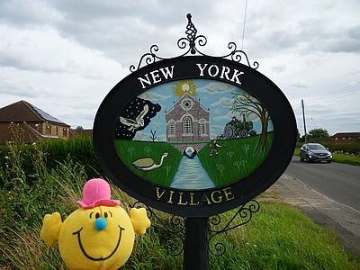 Mr M in front of New York Village sign